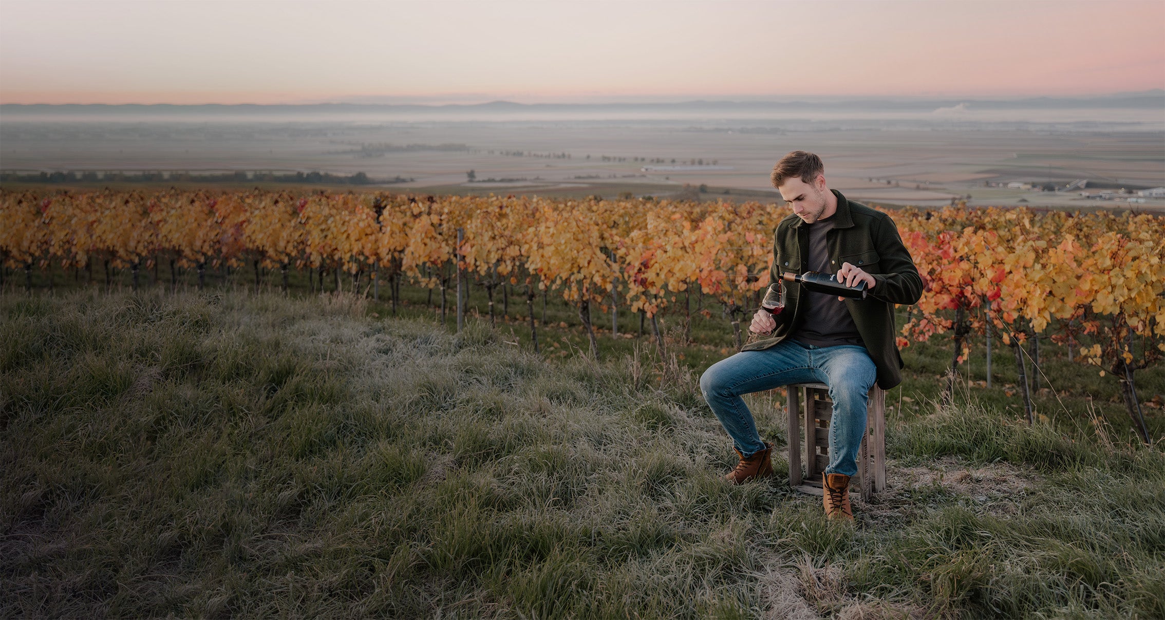 Patrick schenkt sich im Weingarten ein Glas Wein ein.