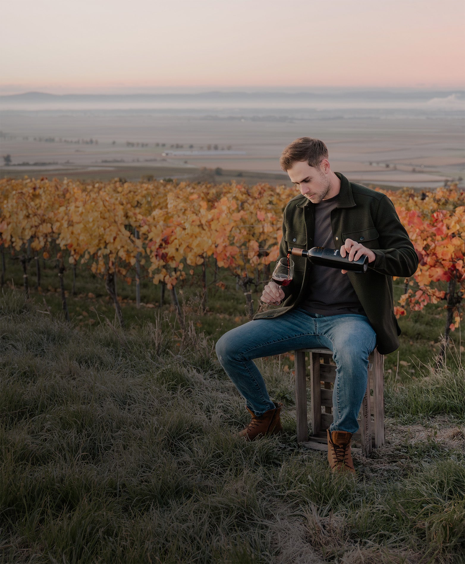 Patrick schenkt sich im Weingarten ein Glas Wein ein.